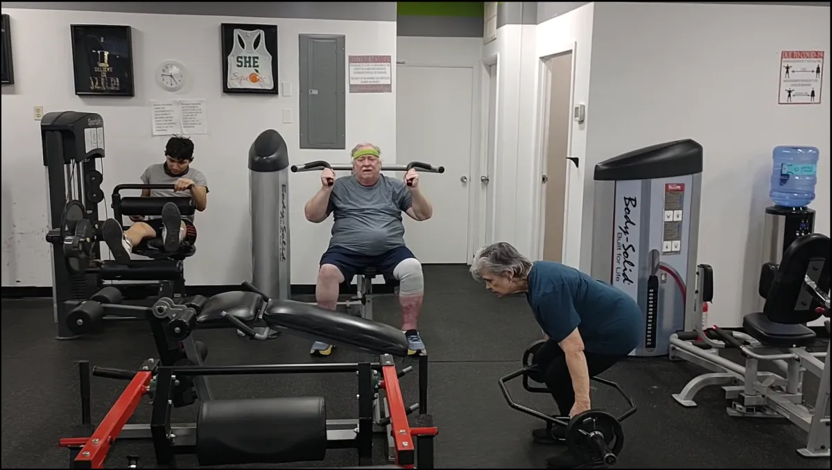 Three members training on machines and a trap bar on the Year 20Fit floor